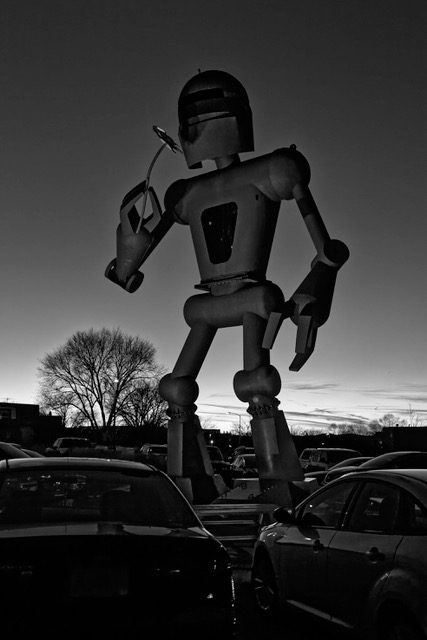 Mustavalkoinen kuva robottipatsaasta parkkipaikalla
